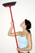Woman cleaning ceiling with a broom.