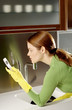 Photo: Woman text messaging while washing dishes in the kitchen. Woman text messaging while washing dishes in the kitchen.