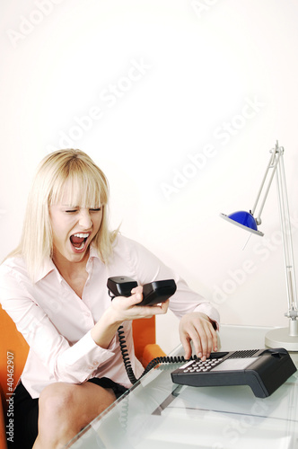Photo: Businesswoman screaming into the phone receiver. Businesswoman screaming into the phone receiver.