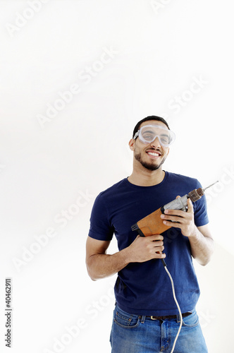 Photo: Man with goggles holding a drill. Man with goggles holding a drill.