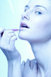 Woman applying lipstick on her lips.