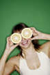 Woman covering her eyes with cut oranges.