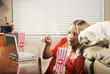 Girl eating popcorn while watching movie on the portable dvd player.