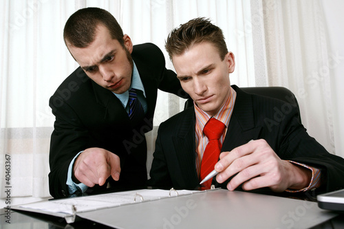 Photo: Businessman and his assistant reading through a contract. Businessman and his assistant reading through a contract.