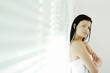 Woman folding her arms while leaning against window blinds