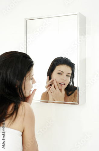 Foto: Woman checking her face on the mirror Woman checking her face on the mirror