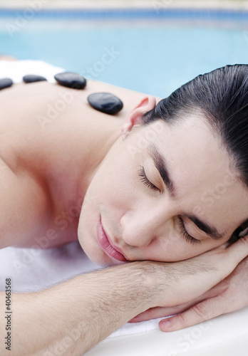 Photo: Man lying forward with therapeutic hot stones on his back Man lying forward with therapeutic hot stones on his back