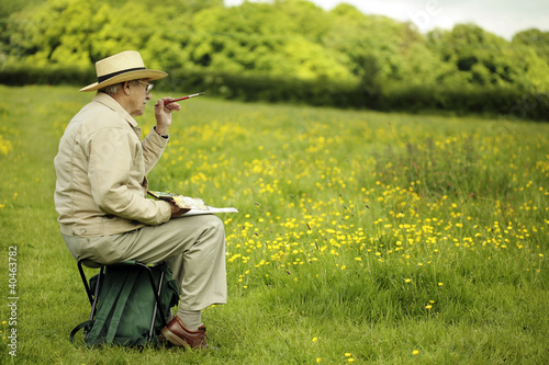 Photo: Senior man sitting on a chair drawing Senior man sitting on a chair drawing