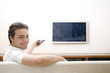 Man sitting on the couch holding a television remote control