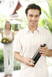 Man holding a bottle of drink with his girlfriend holding a basket of flowers