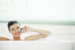 Woman talking on the phone while sitting in the bathtub