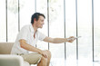 Man sitting on the couch holding a television remote control