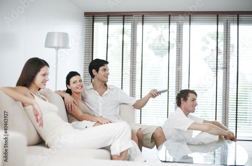 Photo: Men and women watching television at home Men and women watching television at home