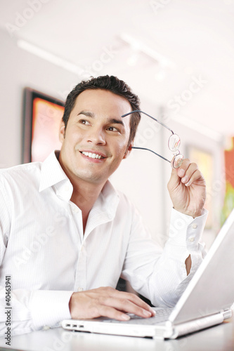 Foto: Man taking out his glasses while using laptop Man taking out his glasses while using laptop