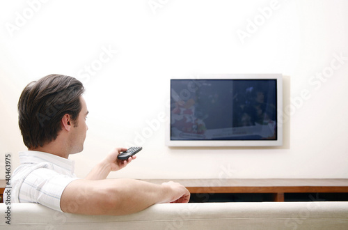 Photo: Man controlling television with a remote control Man controlling television with a remote control