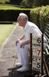 Senior man sitting on a bench in a bowling green