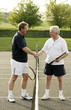 Two men shaking hands in a tennis court