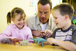 Male teacher showing his students some dinosaur figurines