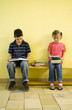 Boy and girl sitting on the bench with books on the lap