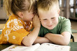 Girl whispering something into boy's ear