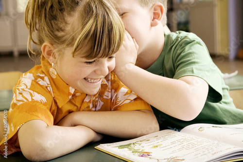 Foto: Boy whispering something into girl's ear Boy whispering something into girl's ear