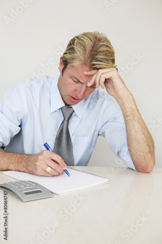 Photo: Businessman frowning at the sight of his expenses Businessman frowning at the sight of his expenses