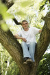 Young man sitting on top of tree