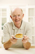 Photo: Senior man holding a plate of cake Senior man holding a plate of cake