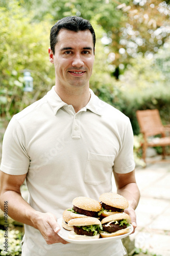 Photo: Man holding a plate of burgers Man holding a plate of burgers