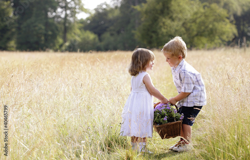 Photo: Little boy helping little girl with the basket of flowers Little boy helping little girl with the basket of flowers