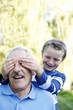 Boy covering his grandfather's eyes