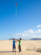 mother and son fly a kite at natural reserve dunes of Corralejo,