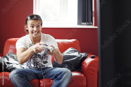 Photo: Man sitting on the couch playing video game console Man sitting on the couch playing video game console