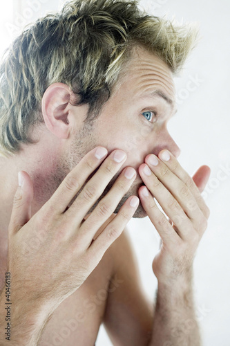 Photo: Man checking his face in the mirror Man checking his face in the mirror
