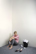 Businesswoman sitting on the floor holding organizer, a dustbin full of crumpled paper balls beside her