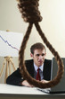 Businessman using laptop, view through a noose