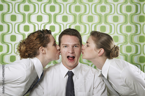 Photo: Two businesswomen kissing businessman on cheeks Two businesswomen kissing businessman on cheeks