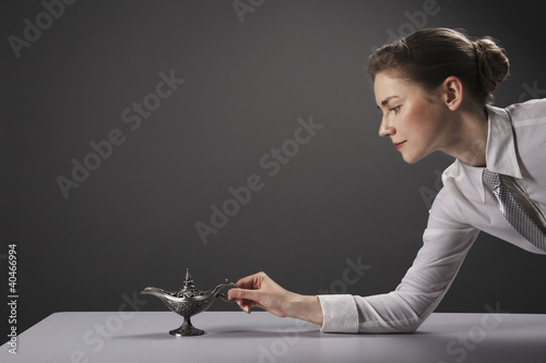 Photo: Businesswoman putting magic lamp on the table Businesswoman putting magic lamp on the table