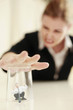 Businesswoman covering a tiny businessman under a transparent glass