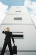Businesswoman looking up at a giant cabinet