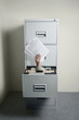 Businesswoman's hand coming out from an opened cabinet holding papers