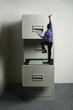 Businessman climbing up a giant cabinet