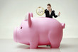 Businesswoman putting in a giant sized coin into piggy bank's slot