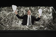 Businessman standing in a pile of paper clips, screaming while holding papers