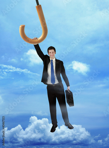 Photo: Businessman holding on to a flying umbrella Businessman holding on to a flying umbrella