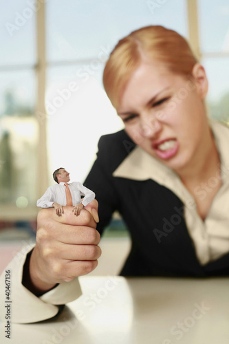 Photo: Businesswoman squeezing a tiny businessman Businesswoman squeezing a tiny businessman