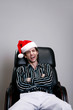 Foto: Businessman with christmas hat sitting on the chair laughing Businessman with christmas hat sitting on the chair laughing