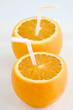 Drinking straws being inserted in oranges.