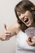 Woman showing thumbs up while holding playing cards