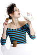 Woman holding biscuit while drinking a bottle of milk